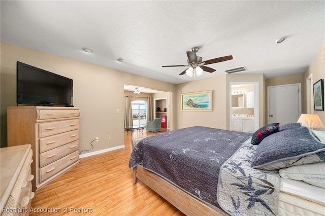 bedroom with ceiling fan, light wood finished floors, ensuite bath, baseboards, and visible vents