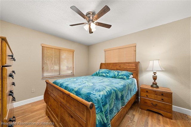 bedroom with a ceiling fan, baseboards, and light wood-type flooring