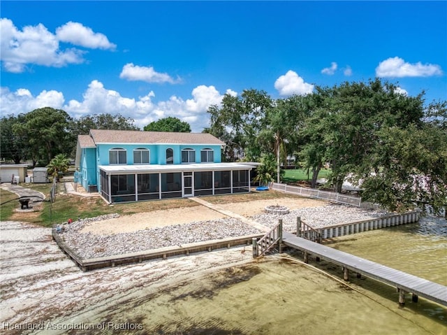 back of property with a sunroom, a water view, and stucco siding