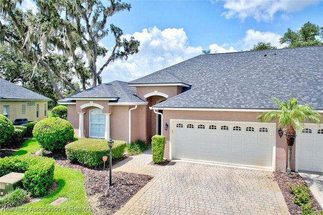 3013 Royal Oaks Ct, Sebring, FL 33875 - view of front of home featuring roof with shingles, an attached garage, stucco siding, and decorative driveway