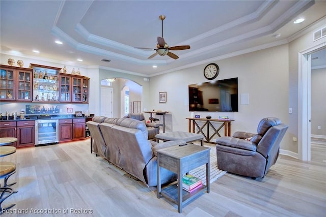 3013 Royal Oaks Ct, Sebring, FL 33875 - living area featuring beverage cooler, bar with sink, a tray ceiling, arched walkways, and crown molding