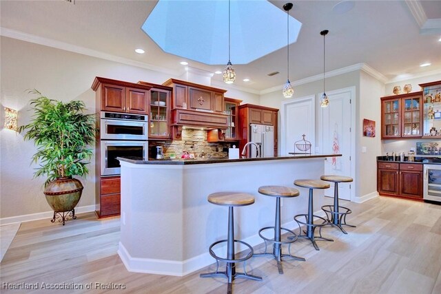 3013 Royal Oaks Ct, Sebring, FL 33875 - kitchen with white fridge with ice dispenser, double oven, dark countertops, custom range hood, and crown molding