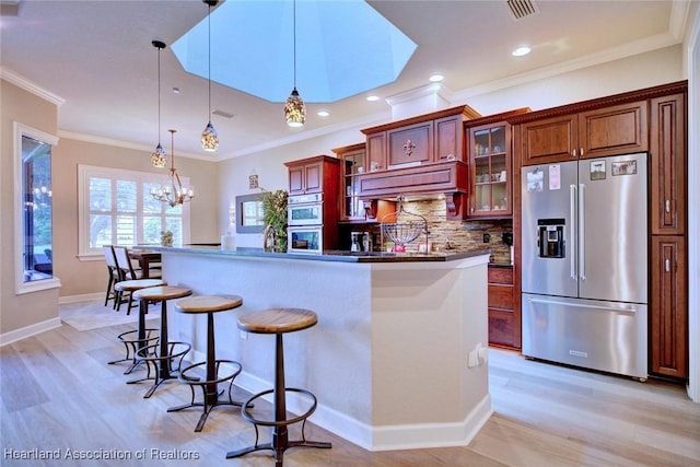 3013 Royal Oaks Ct, Sebring, FL 33875 - kitchen featuring appliances with stainless steel finishes, light wood-style floors, a kitchen bar, backsplash, and a center island