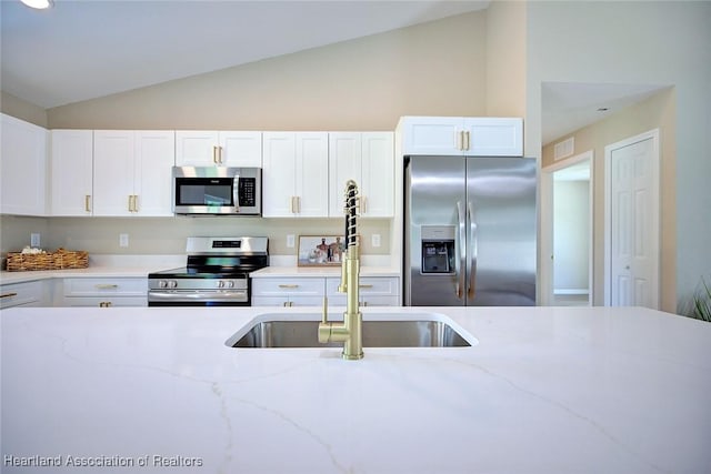 4001 Simca St, Sebring, FL 33872 - kitchen featuring stainless steel appliances, lofted ceiling, a sink, white cabinets, and light stone countertops