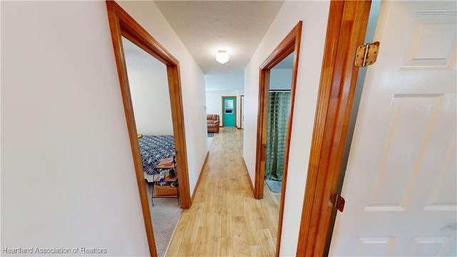 hallway featuring a textured ceiling and light hardwood / wood-style flooring