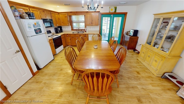 kitchen featuring white appliances, sink, light hardwood / wood-style flooring, an inviting chandelier, and hanging light fixtures