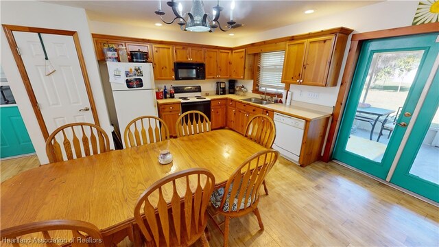 kitchen featuring sink, hanging light fixtures, light hardwood / wood-style flooring, a chandelier, and white appliances