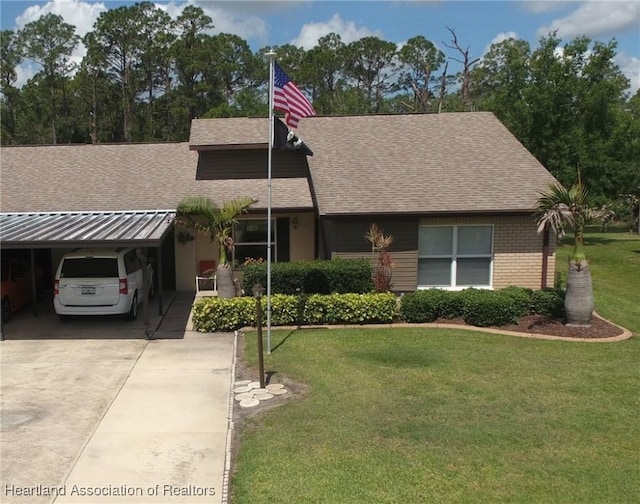 view of front of property featuring an attached carport, brick siding, a front yard, and roof with shingles