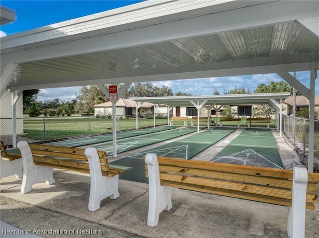 surrounding community featuring a lawn, shuffleboard, and fence