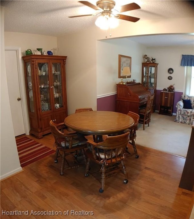 dining room featuring light wood-style floors, a textured ceiling, and ceiling fan