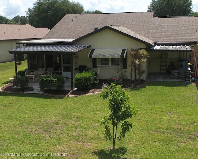 rear view of property with metal roof, a lawn, a shingled roof, and stucco siding