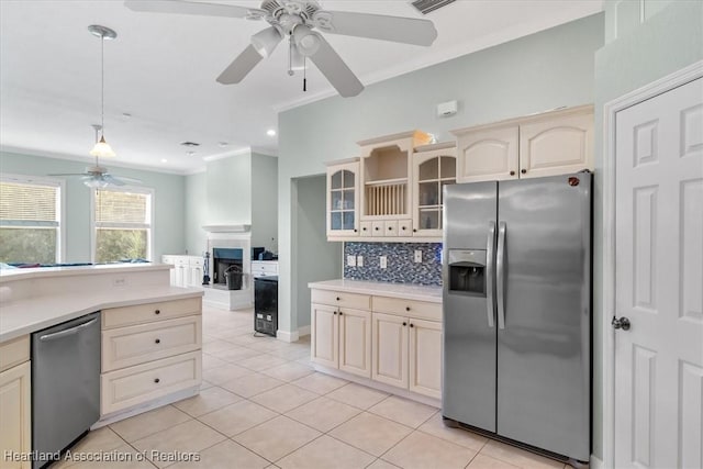 kitchen with appliances with stainless steel finishes, tasteful backsplash, ceiling fan, crown molding, and light tile patterned floors