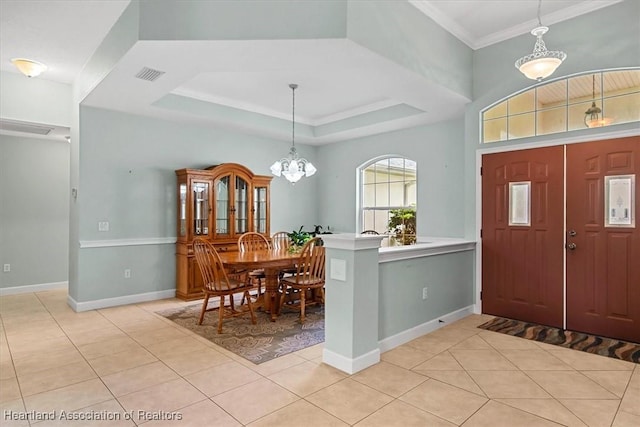 tiled entryway featuring an inviting chandelier, a raised ceiling, and ornamental molding