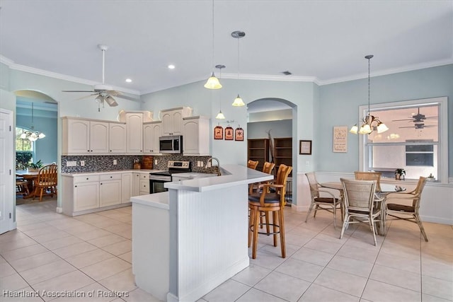 kitchen featuring backsplash, kitchen peninsula, hanging light fixtures, and appliances with stainless steel finishes