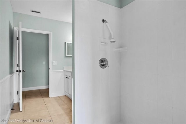 bathroom with tile patterned floors, a shower, and vanity