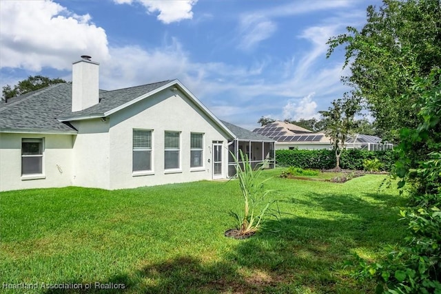 back of property with a lawn and glass enclosure