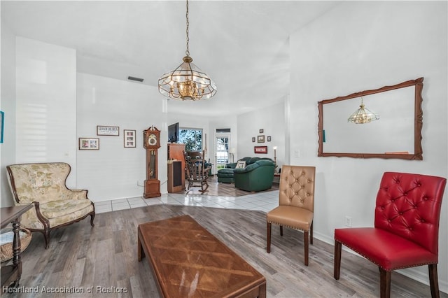 sitting room with baseboards, a notable chandelier, wood finished floors, and visible vents