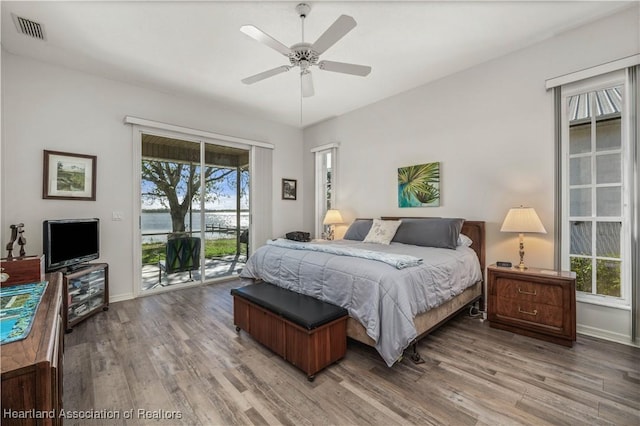 bedroom with baseboards, access to exterior, wood finished floors, and visible vents