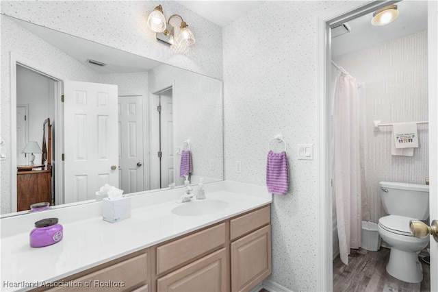 bathroom featuring vanity, wallpapered walls, wood finished floors, and visible vents