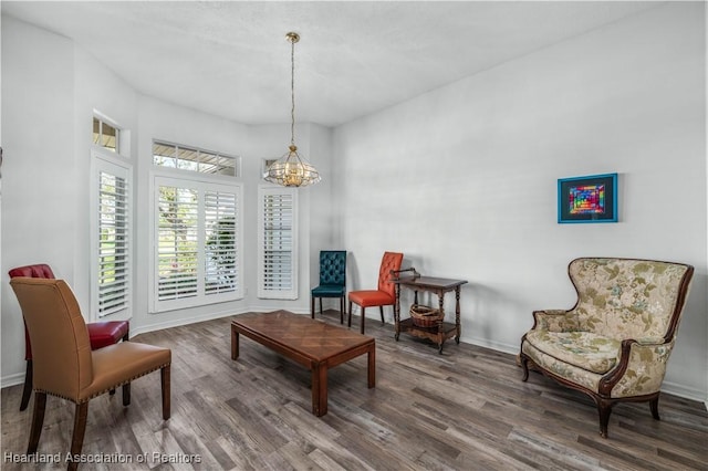 living area with baseboards, wood finished floors, and a chandelier