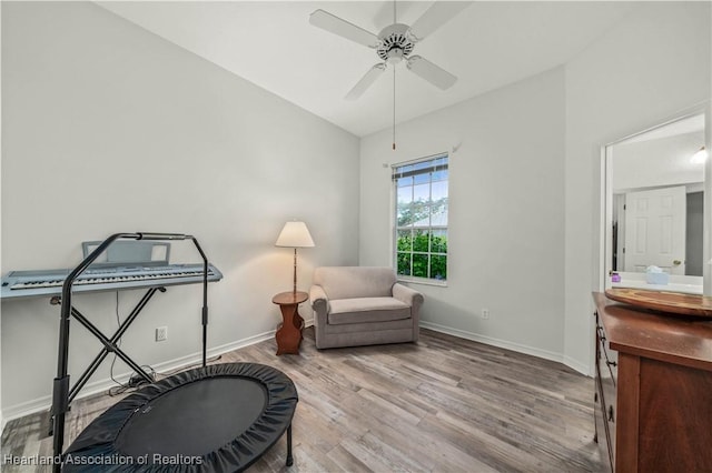 sitting room with baseboards, ceiling fan, vaulted ceiling, and wood finished floors