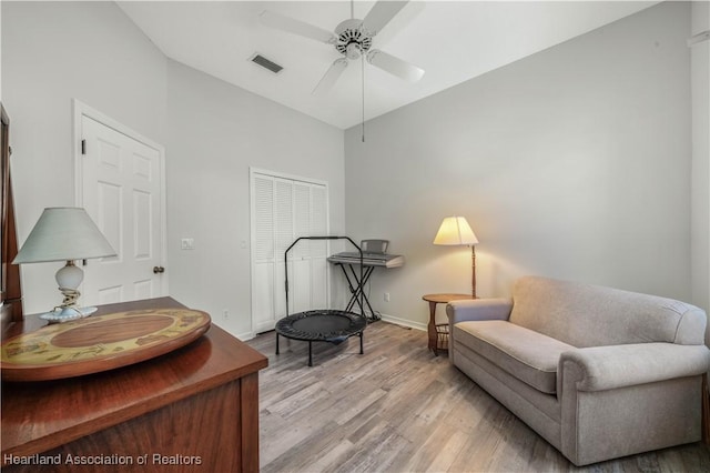 living area featuring visible vents, baseboards, ceiling fan, high vaulted ceiling, and light wood finished floors