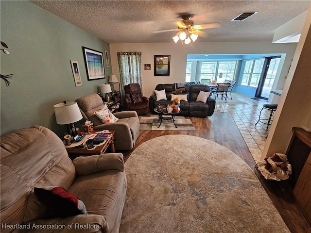 living room with hardwood / wood-style flooring, ceiling fan, and a textured ceiling