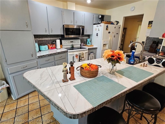 kitchen with backsplash, kitchen peninsula, a breakfast bar area, and white appliances