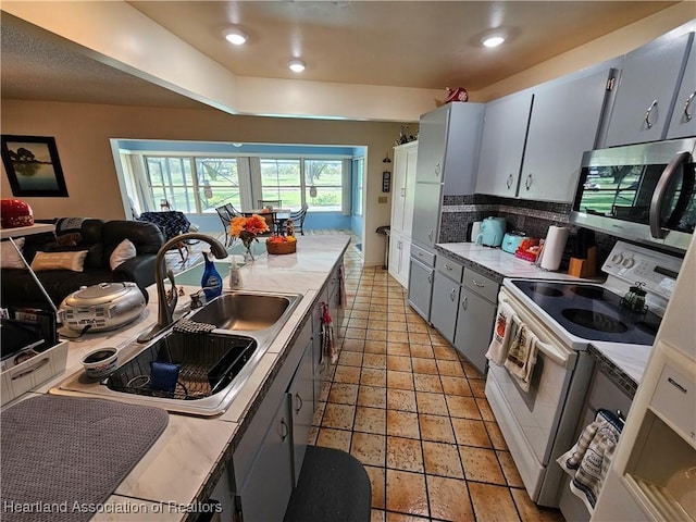 kitchen with gray cabinetry, sink, white electric stove, light tile patterned floors, and tasteful backsplash