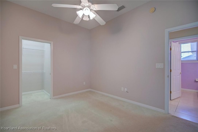 unfurnished bedroom with visible vents, a closet, baseboards, light colored carpet, and a spacious closet