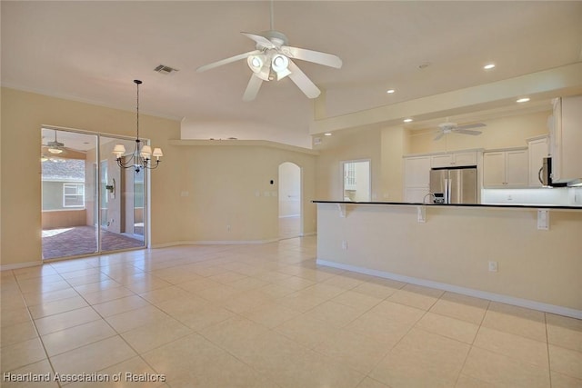 interior space featuring visible vents, baseboards, ceiling fan with notable chandelier, arched walkways, and light tile patterned flooring