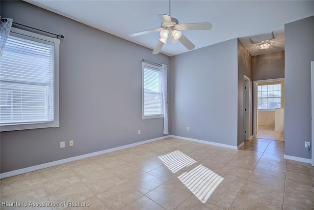 empty room with visible vents, light tile patterned floors, a ceiling fan, and baseboards