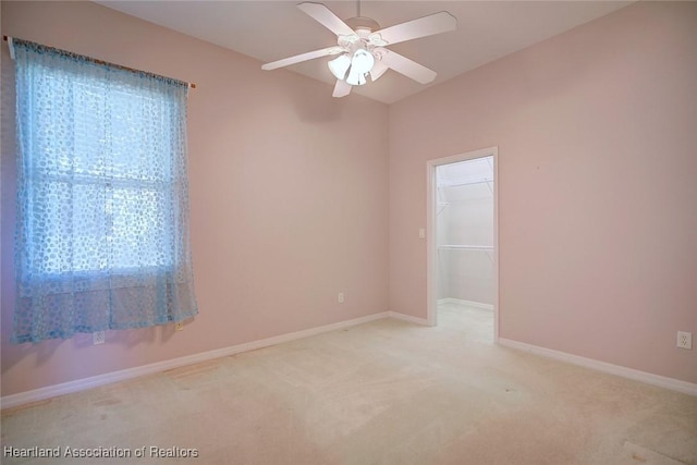 spare room featuring baseboards, light carpet, and ceiling fan