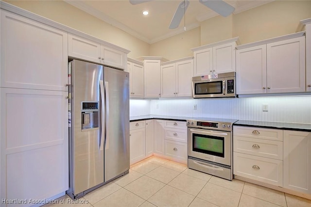 kitchen with light tile patterned floors, ceiling fan, white cabinets, appliances with stainless steel finishes, and crown molding