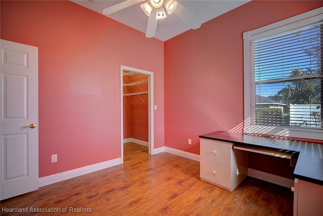 unfurnished office featuring baseboards, light wood-type flooring, ceiling fan, and vaulted ceiling