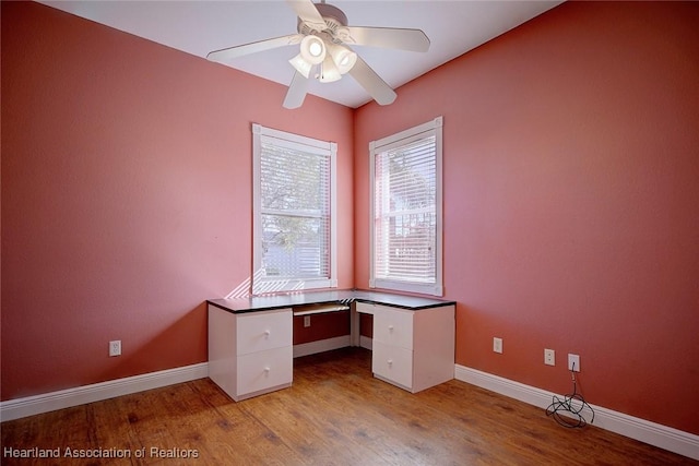 unfurnished office featuring ceiling fan, baseboards, and wood finished floors