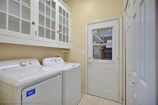 washroom featuring cabinet space, light tile patterned floors, and washing machine and dryer