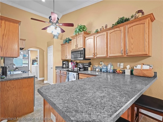 kitchen with ceiling fan, kitchen peninsula, appliances with stainless steel finishes, light tile patterned floors, and ornamental molding