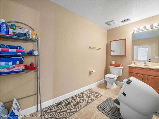 bathroom featuring tile patterned flooring, vanity, a textured ceiling, and toilet