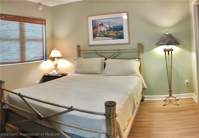 bedroom with light hardwood / wood-style floors and crown molding