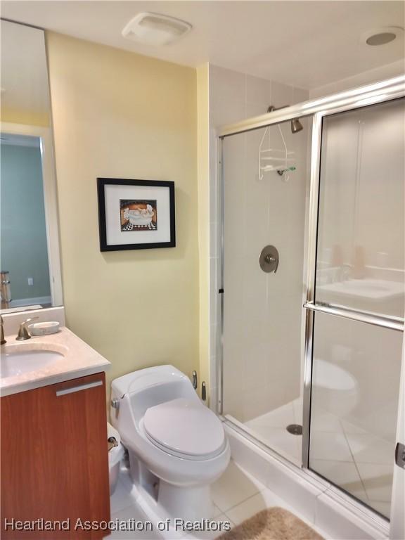 bathroom with tile patterned flooring, vanity, an enclosed shower, and toilet