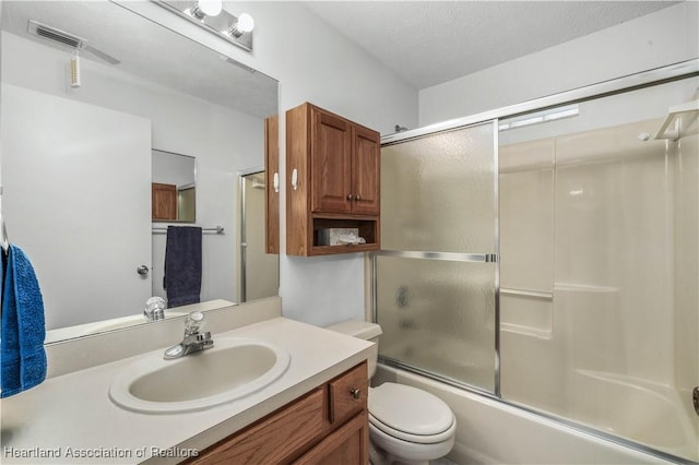 full bathroom with vanity, enclosed tub / shower combo, a textured ceiling, and toilet