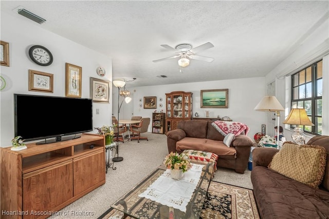 carpeted living room featuring ceiling fan and a textured ceiling