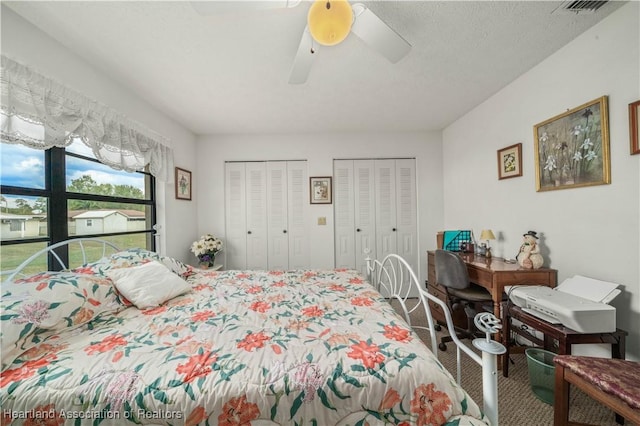 bedroom with multiple closets, ceiling fan, and a textured ceiling