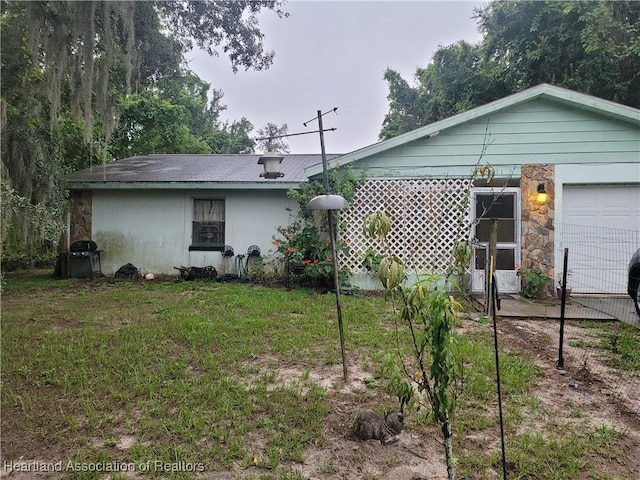 rear view of house featuring a garage and a yard