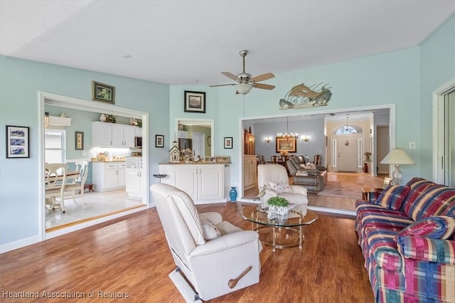 living room with ceiling fan with notable chandelier and light hardwood / wood-style floors