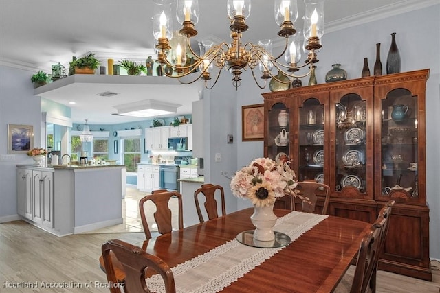 dining space featuring light wood-type flooring, crown molding, and an inviting chandelier