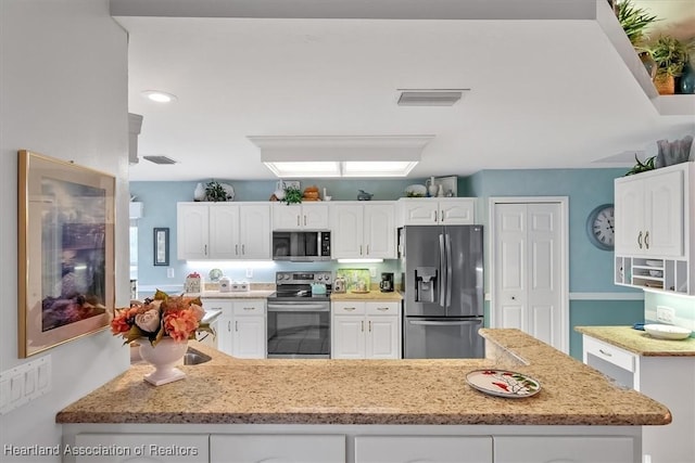 kitchen featuring light stone countertops, kitchen peninsula, stainless steel appliances, and white cabinetry