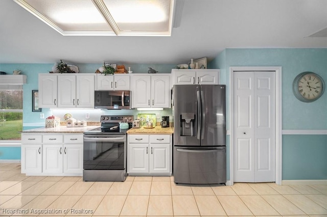 kitchen featuring white cabinets, light tile patterned floors, stainless steel appliances, and light stone countertops