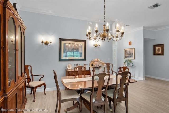 dining space featuring a chandelier, light hardwood / wood-style flooring, and crown molding